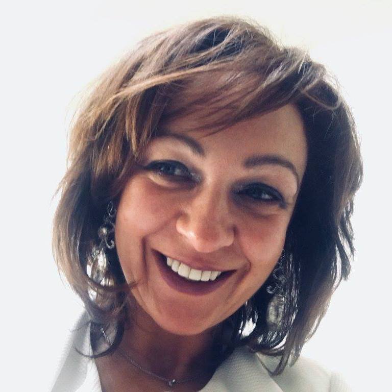 Lachende portretfoto van Chantal met halflang bruin haar, lichte blouse, tegen een witte achtergrond