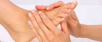 Close-up van twee handen die een verzorgde voet met nette nagels masseren
